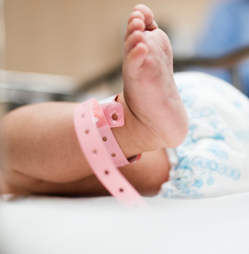 Image of a baby's foot, with a pink hospital band around its ankle.